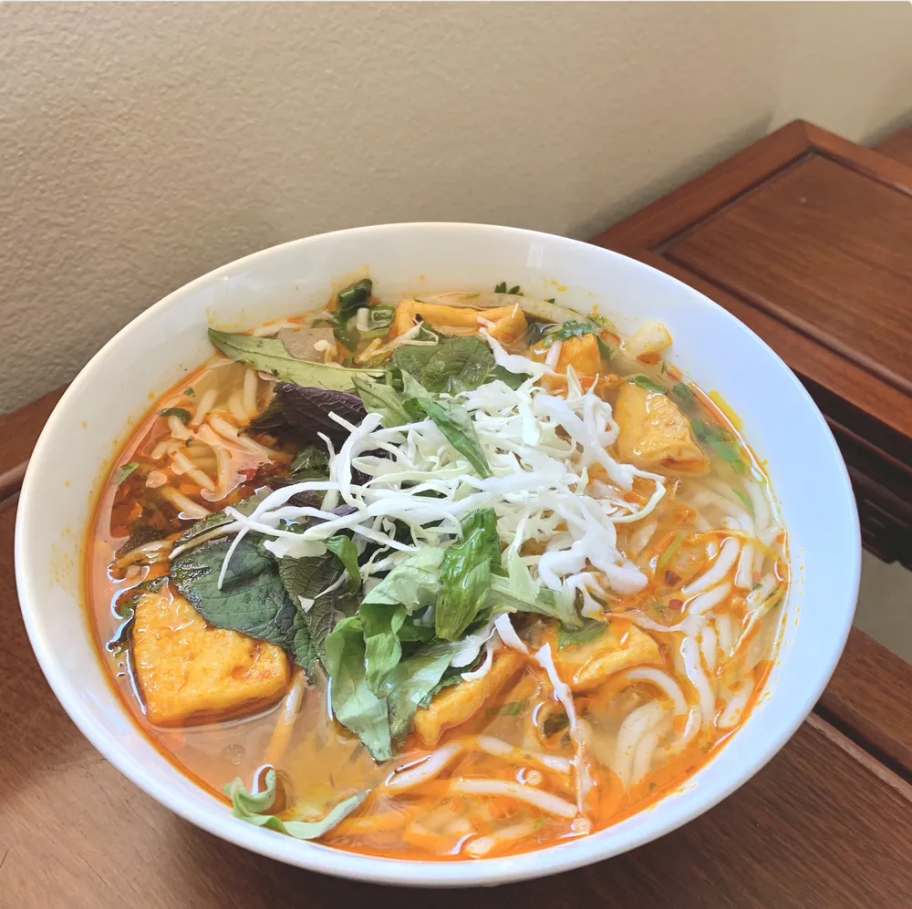 steaming noodle soup with tofu and fresh herbs